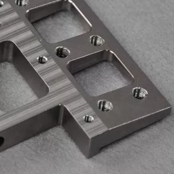 Close up of a brushed titanium alloy metal bracket with threaded holes
